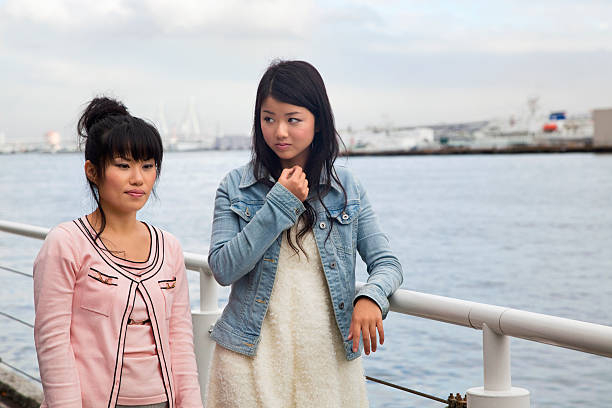 istock Two sad Japanese girls walk at waterfront. 185318076