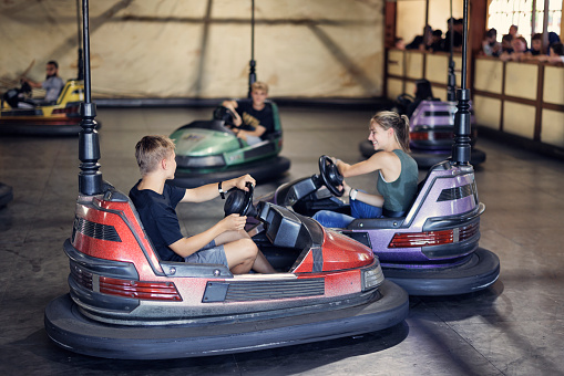 Teenagers having fun riding bumper cars in funfair amusement park. 
Shot with Canon R5.