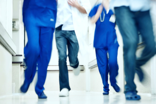 Blurred image of the legs of a group of doctors running in a hospital