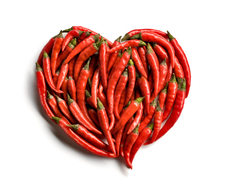 A heart made of red hot peppers on white background with a soft shadow.Related images: