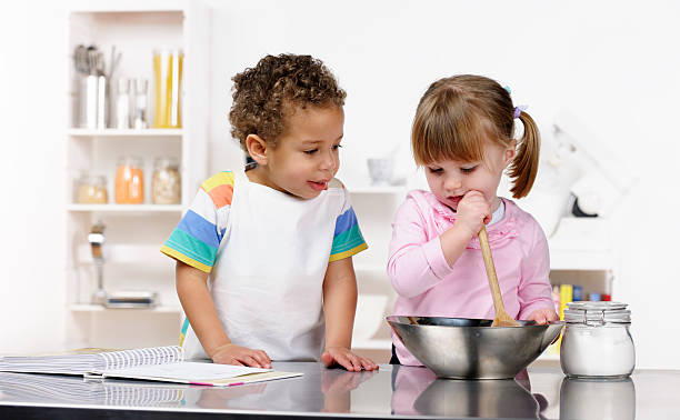 piccolo ragazzo e ragazza preparare il cibo in cucina - baby1 foto e immagini stock