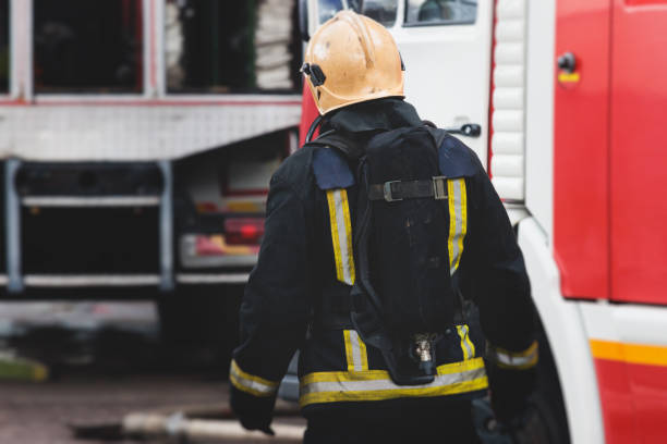 gruppe von feuerwehrmännern in schutzuniform während des löscheinsatzes in den straßen der stadt, feuerwehrbrigade mit dem löschfahrzeug im hintergrund, rettungs- und rettungsdienst - fire department courage forest fire heroes stock-fotos und bilder