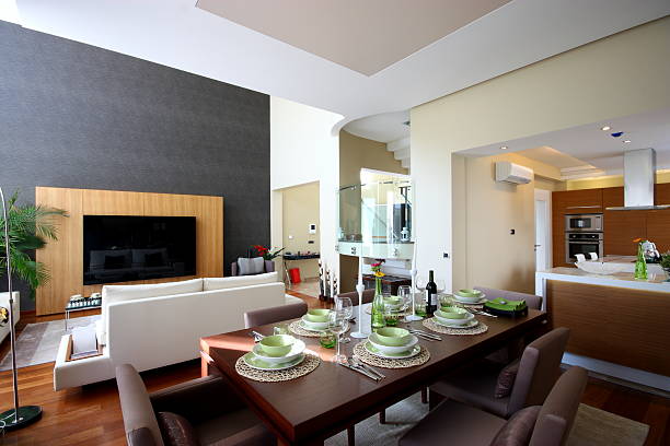 Wide-angle raster photograph capturing a clean, well-lit domestic interior space designed for entertaining. Features a long dining table, built-in kitchen cabinets, and stylish finishes. Useful for real estate listings, architectural showcases, or interior catalogs.