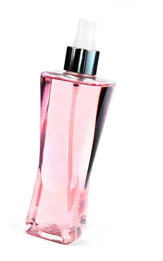 A white isolation of a clear glass perfume bottle filled with pink perfume