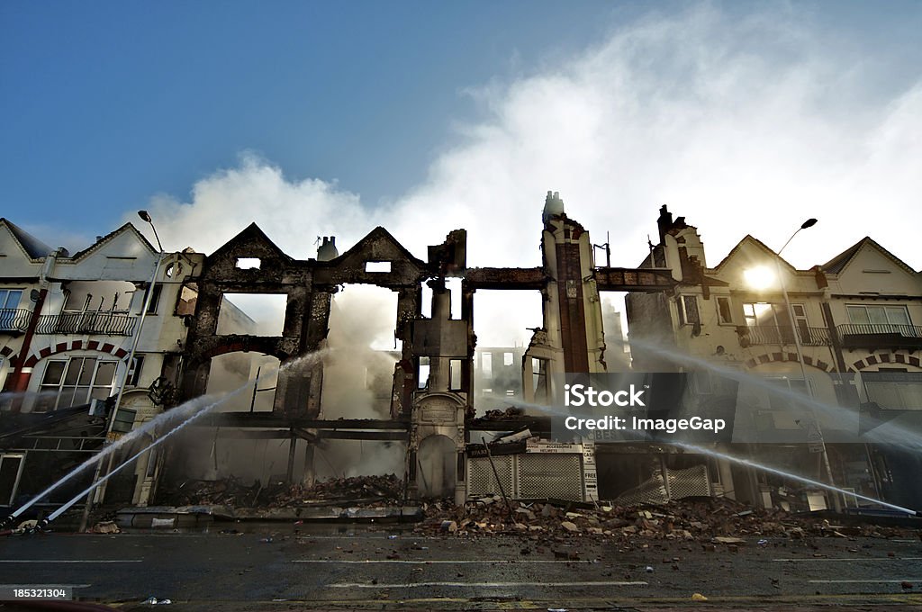 Fire insurance Automated hoses directing water at a smoldering row of burnt out buildings Fire - Natural Phenomenon Stock Photo