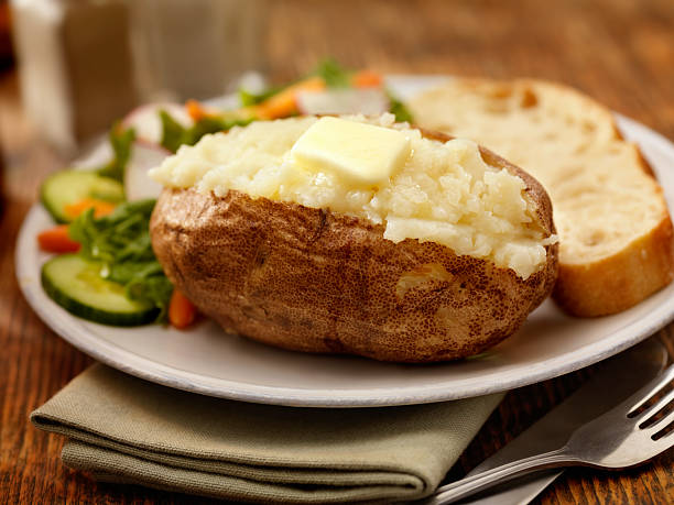 Jacket Potato Baked Potato with Melting Butter a Side Salad and Garlic Bread -Photographed on Hasselblad H3D-39mb Camera baked potato stock pictures, royalty-free photos & images