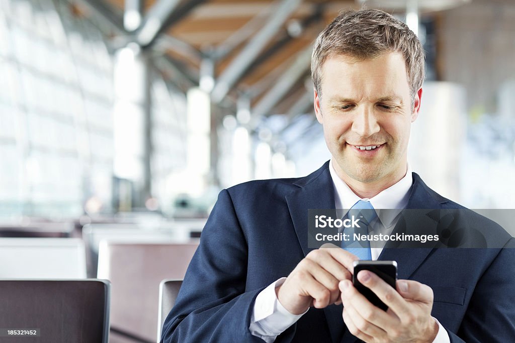 Empresário escrevendo uma mensagem de texto em seu telefone no aeroporto - Royalty-free 30-39 Anos Foto de stock