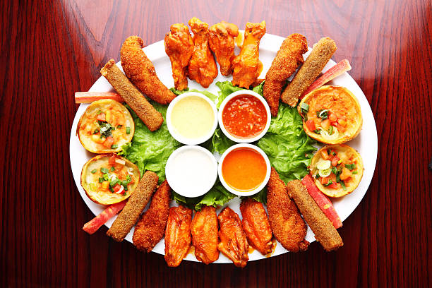 Appetiser Platter Grilled Buffalo Chicken Wings, Potato Skins "Starter platter with fried chicken wings, Buffalo wings, chicken and fish sticks, baked potato skins served with hot sauce, garlic dip and sour cream dip." appetiser stock pictures, royalty-free photos & images