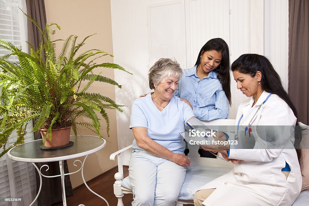 Senior woman receiving blood pressure check at home. Doctor. Senior woman having blood pressure checked at home.  Family member by her side. Blood Pressure Gauge Stock Photo