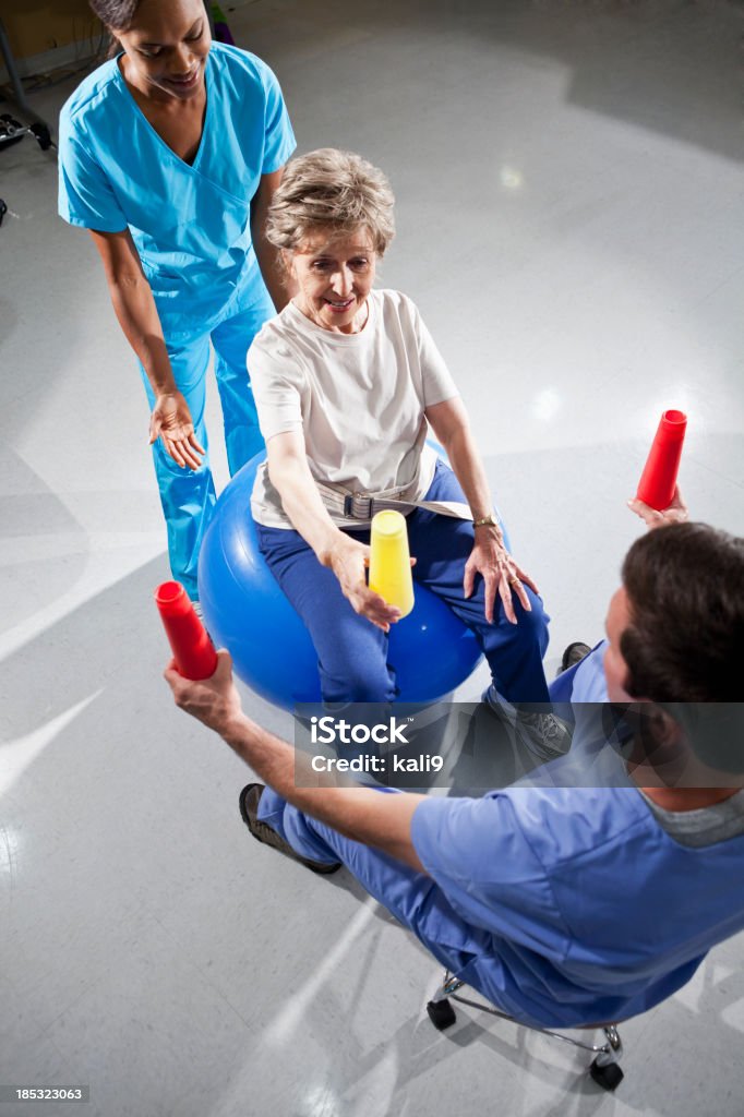 Mulher sênior com físico terapeutas usando uma bola de estabilidade e c - Foto de stock de Terapia Ocupacional royalty-free