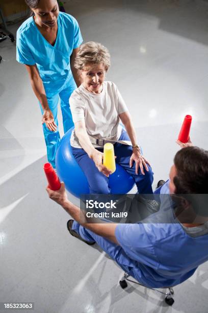 Foto de Mulher Sênior Com Físico Terapeutas Usando Uma Bola De Estabilidade E C e mais fotos de stock de Terapia Ocupacional