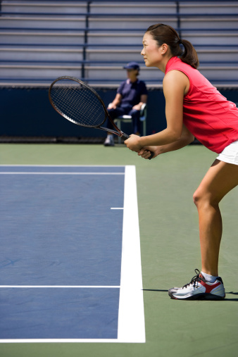 Young Asian female tennis player ready for service return.