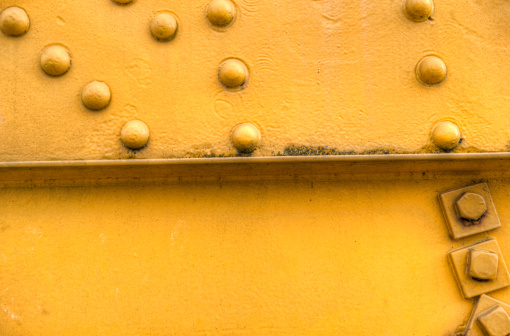 yellow steel girder / the rivets are riveting / and hold it in place