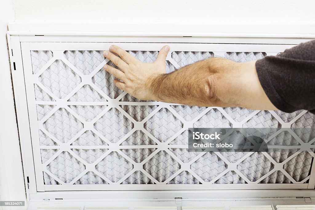 Replacing AC Filter Man replacing A/C filter for a home air conditioning system. Air Conditioner Stock Photo