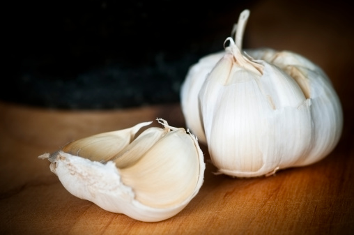 Royalty free stock photo of one whole fresh garlic on table with focus on the foreground.
