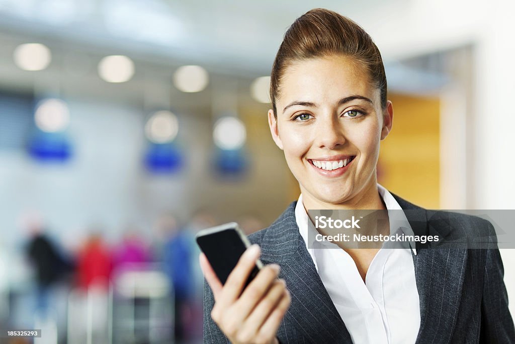 笑顔のビジネス女性、携帯電話で空港 - 1人のロイヤリティフリーストックフォト