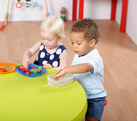 Toddlers/ pre-schoolers having a healthy snack in a nursery setting.