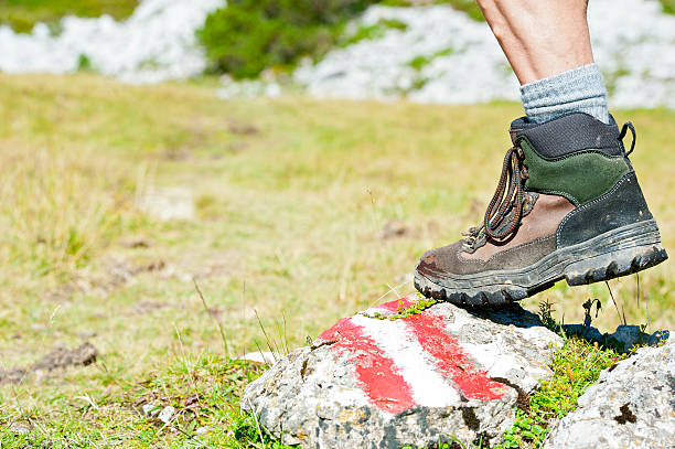 Closeup of a hiking boot in the mountains. The red-white-red way marker is typical for the Austrian alps.