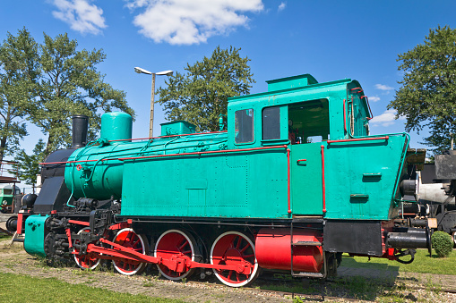 Summer view of a beautiful green steam locomotive against blue sky