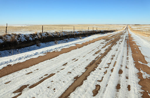 Snow covered dirt road surrounded by fields