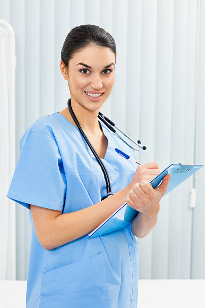 istock Beautiful young nurse filling medical documents 185328880