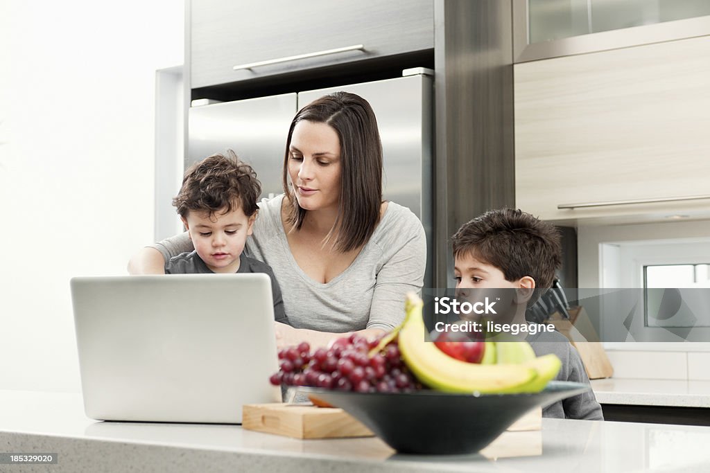 Mujer embarazada con sus hijos en la cocina - Foto de stock de 2-3 años libre de derechos