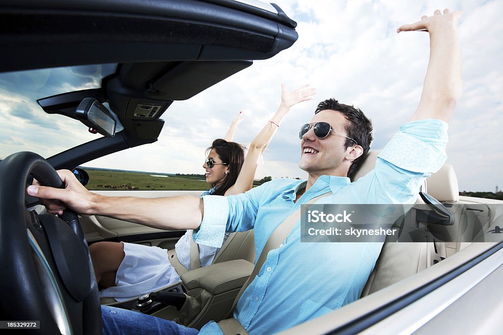 Hermosa pareja sentada en un descapotable coche con aumento de la autoridad de salud - Foto de stock de Actividad libre de derechos