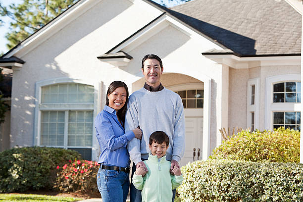 Family in front of house Family standing in front of house.  Mother (30s) is Asian.  Father (40s) and son (6 years) are Asian/Caucasian. in front of stock pictures, royalty-free photos & images