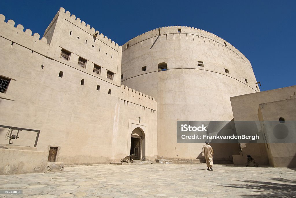 Man at Nizwa Castle Man walking at the courtyard of a 16th Century castle. Nizwa Stock Photo