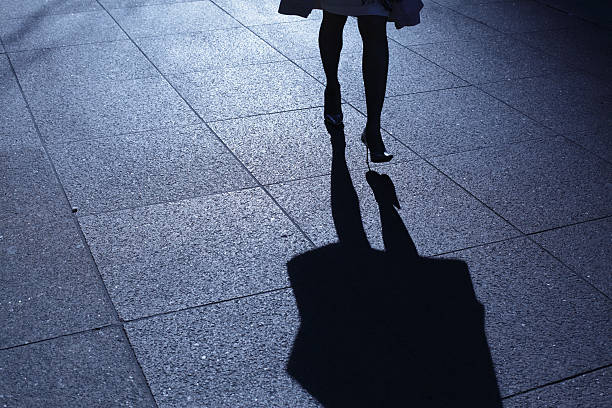 Leg view of a woman in heels walking at night with shadow stock photo