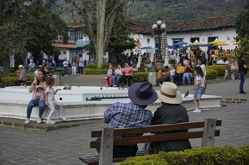 Two gentleman having a conversation in the Parque Principal El Libertador, main square of Jardin, Eje Cafetero, Colombia 2020