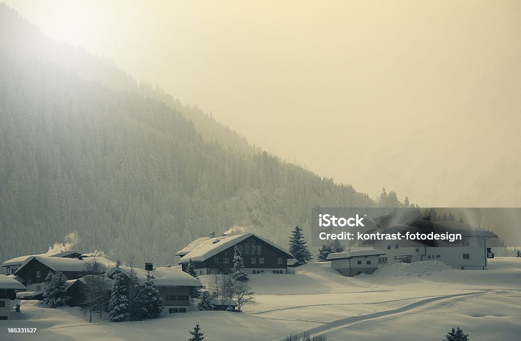 Riezlern, Kleinwalsertal at a misty morning sunrise. "Typical  houses in a snowcovered landscape. Located in Rietzlern, Kleinwalsertal in Austria. There are some snowflakes visible. Cross processed picture with a vintage look." Austria Stock Photo