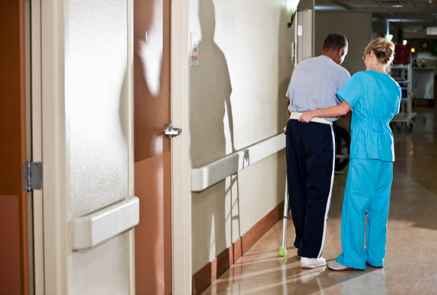 infermiera aiutando il paziente a piedi in un corridoio di ospedale - sc0527 foto e immagini stock