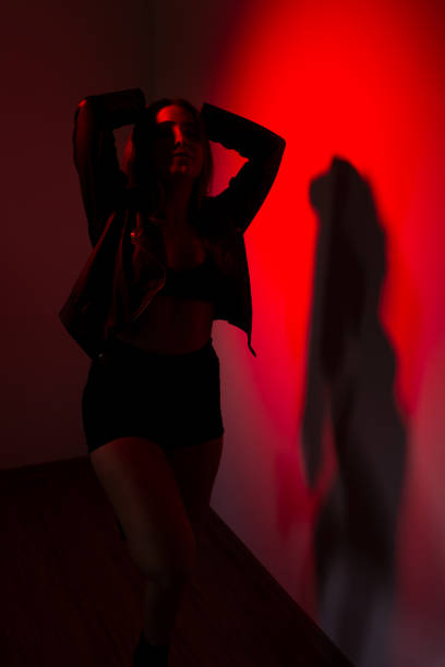 istock Beautiful young model wearing black clothes, with his hand on his head making poses for the bright picture of red. 1853343936
