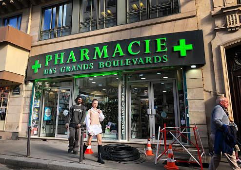 Paris, France: A chic young couple walk past a pharmacy in the 2nd arrondissement.