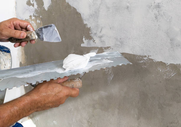 istock Worker puts finishing layer of stucco on the wall using a plastering trowel 1853386570