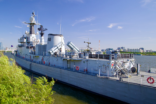 Seoul, South Korea - June 3, 2023: A riverside view of Frigate Seoul on the Han River, showcasing its top deck with missile or torpedo tubes and the prominent antenna tower.