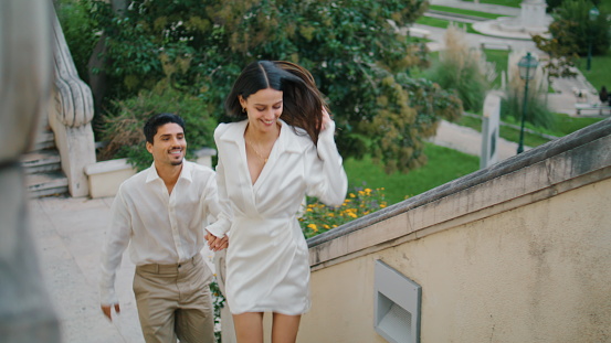 Emotional newlyweds running stairs town. Happy smiling couple kissing embracing