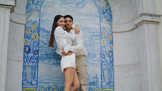 Enamoured people embracing at tile architecture close up. Man tilting woman