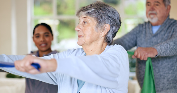 Rehabilitation, recovery or resistance band and a senior couple in their home with a personal trainer. Fitness, physiotherapy or health with an elderly man and woman in their apartment for a workout