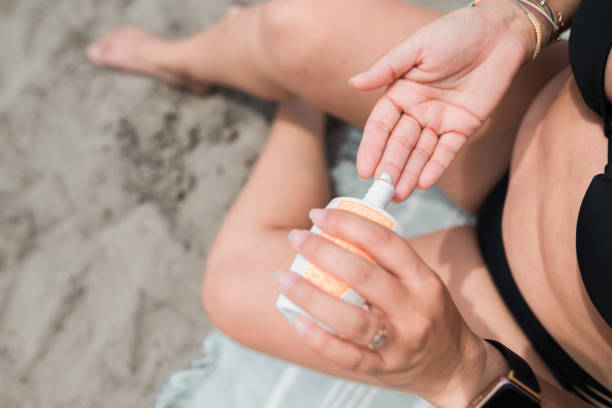 istock Woman slathering sunscreen on her hand at the beach. 1853663333