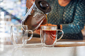 Double walled mugs ensure prolonged temperature and energy preservation. Senior woman hands pouring tea into mugs