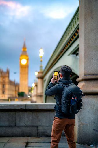 Unrecognizable young Latin man tourist against ancient cathedral in London near tower bridge and Big Ben against