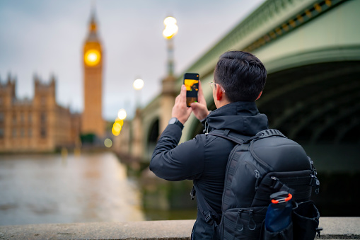 Unrecognizable young Latin man tourist against ancient cathedral in London near tower bridge and Big Ben