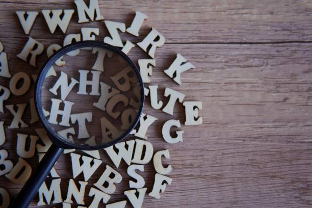 istock Magnifying glass with scattered alphabet letters on the table. 1853682697