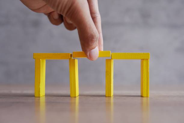 Hand add wooden blocks between the gap to complete the bridge. Hand add wooden blocks between the gap to complete the bridge. Solution, fill the gap concept. bridge hand stock pictures, royalty-free photos & images