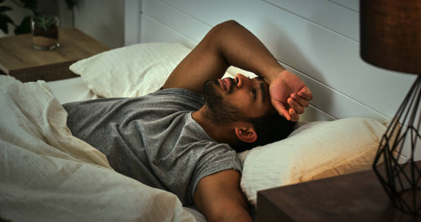 istock Depression, thinking and asian man in a bed with insomnia, fatigue or ptsd memory anxiety. Burnout, conflict and male person in a bedroom with overthinking stress, fear or mistake trauma in a house 1853696884