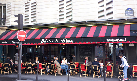 Paris, France: A boy rides a push scooter past Odette & Aimé, a sidewalk cafe on Rue de Maubeuge in the 9th arrondissement.