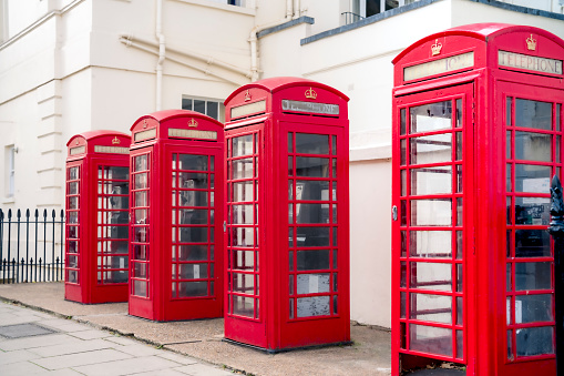 Red telephone booth box on city street on sunny day in London