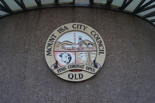Exterior of Mount Isa City Council building with crest, logo or coat of arms and slogan reading Mount Isa City Council QLD ‘Finis Coronat Opus’, Mt Isa, Queensland, Australia